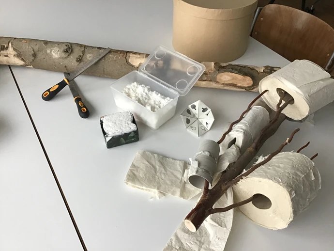 Auf einem Tisch liegen verschiedene Materialien wie Holzst&uuml;cke, Papier, Werkzeuge und Proben.