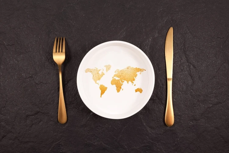 Die Weltkarte auf einem Teller abgebildet, daneben liegt Besteck.