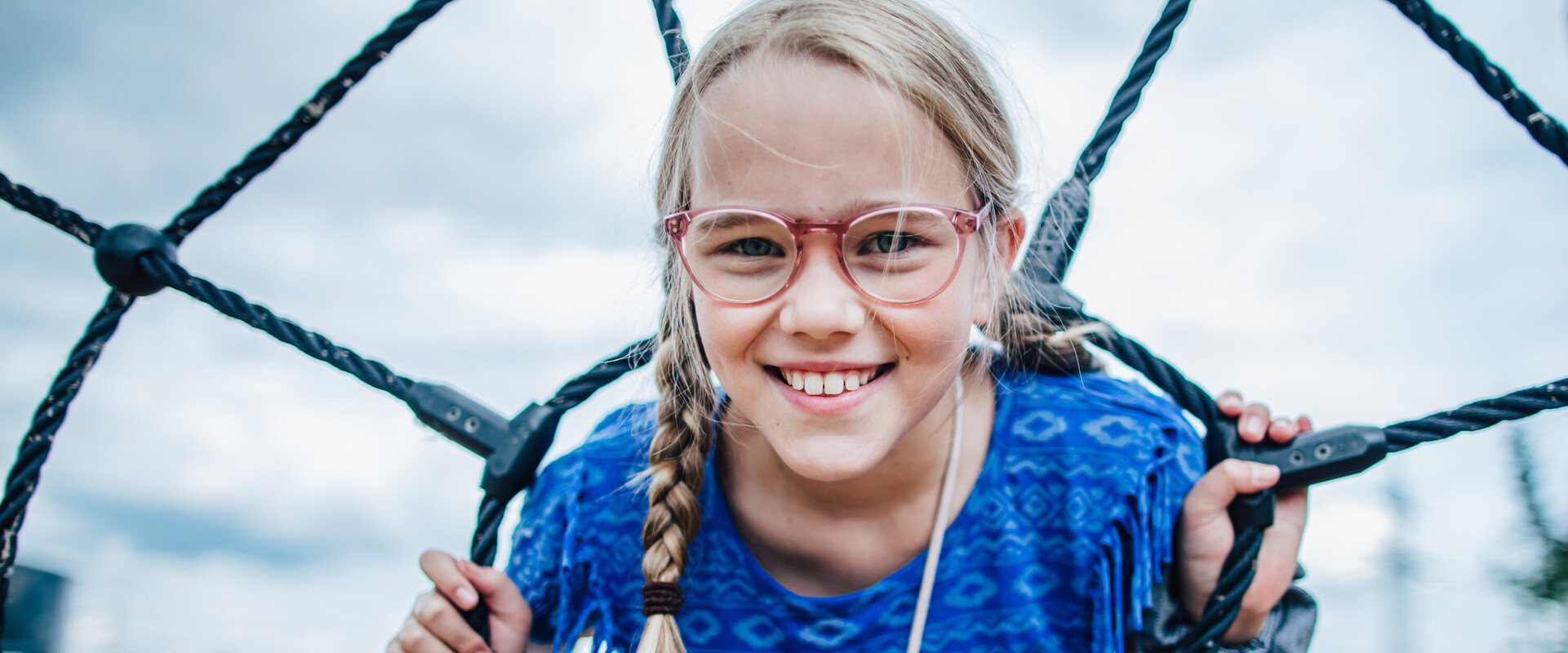 M&auml;dchen steht ihren Kopf durch die Seile am Kletterger&uuml;st.