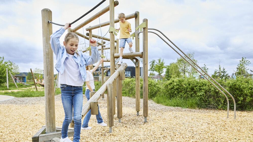 Zwei Kinder turnen auf einem Kletterger&uuml;st.