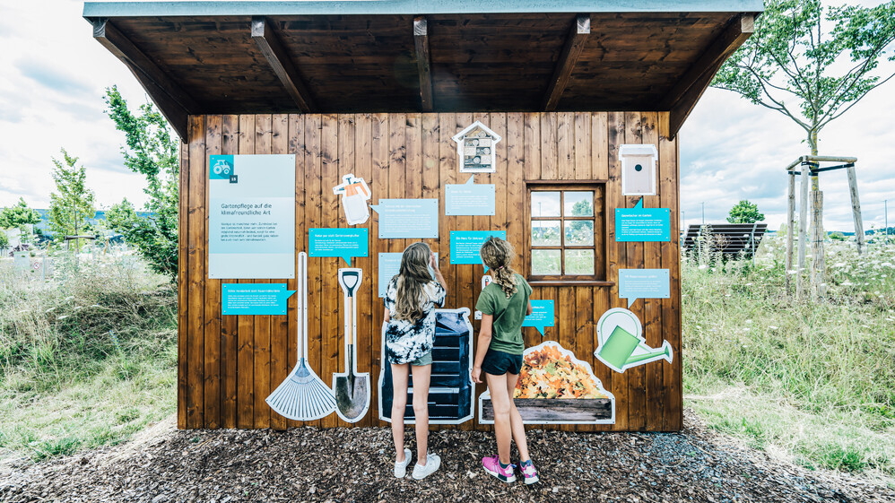 Zwei M&auml;dchen lesen Infotafeln zum Thema nachhaltig G&auml;rtnern.