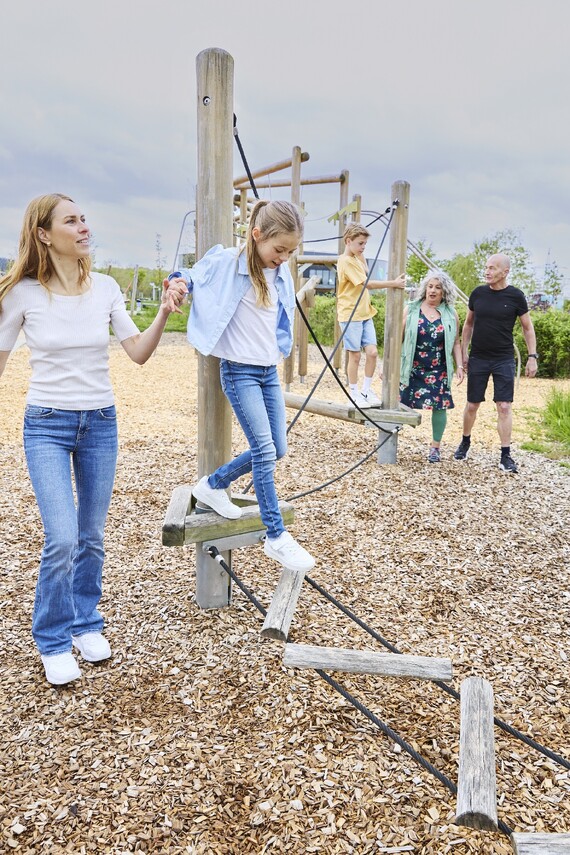 Kinder mit Mutter und Gro&szlig;eltern auf einem Kletterger&uuml;st im Au&szlig;enbereich.