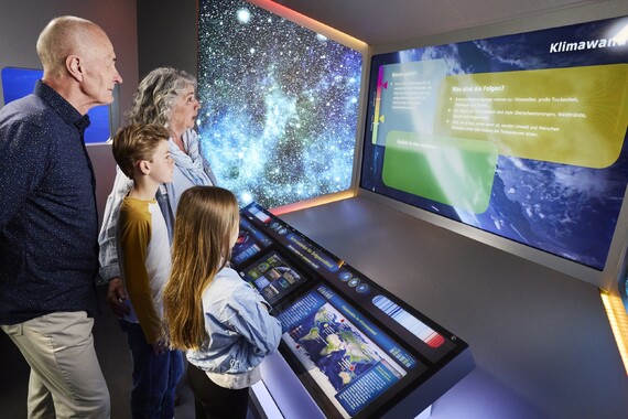 Familie beim Exponat zu Planetaren Grenzen.